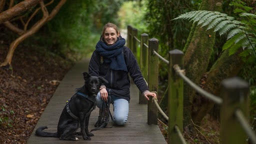 Céline met haar hond Flo op een houten pad in het bos