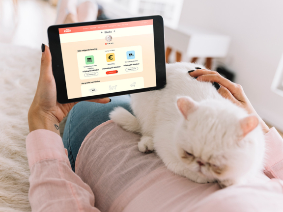 Baasje met witte kat op de app met de tablet en kijkt met extra gemak