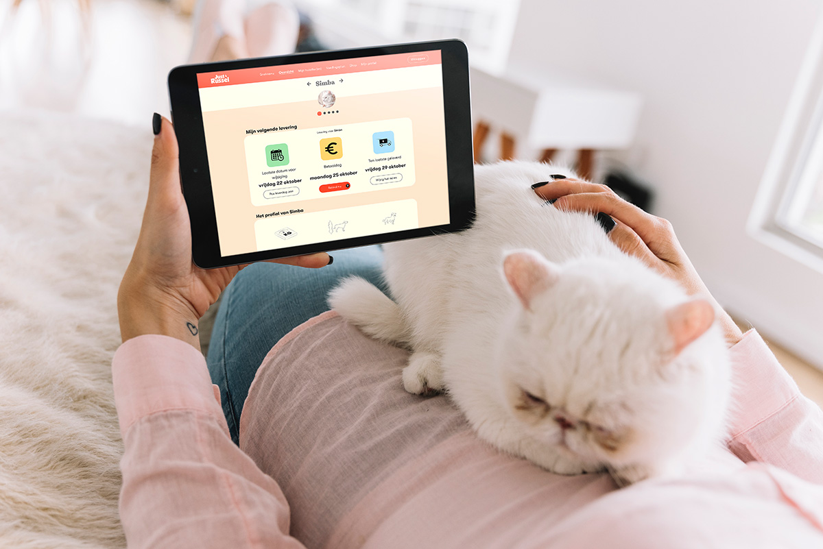Baasje met witte kat op de app met de tablet en kijkt met extra gemak