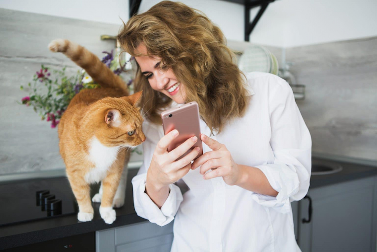 Vrouw op smartphone met een roste kat