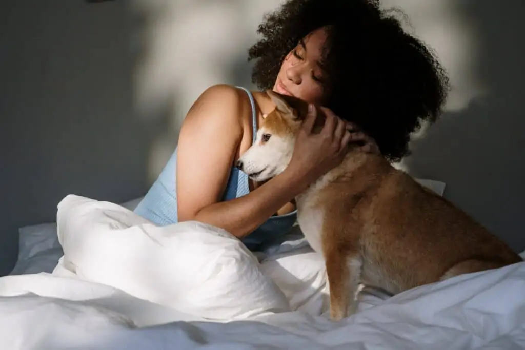 Vrouw aan het knuffelen met hond in haar bed